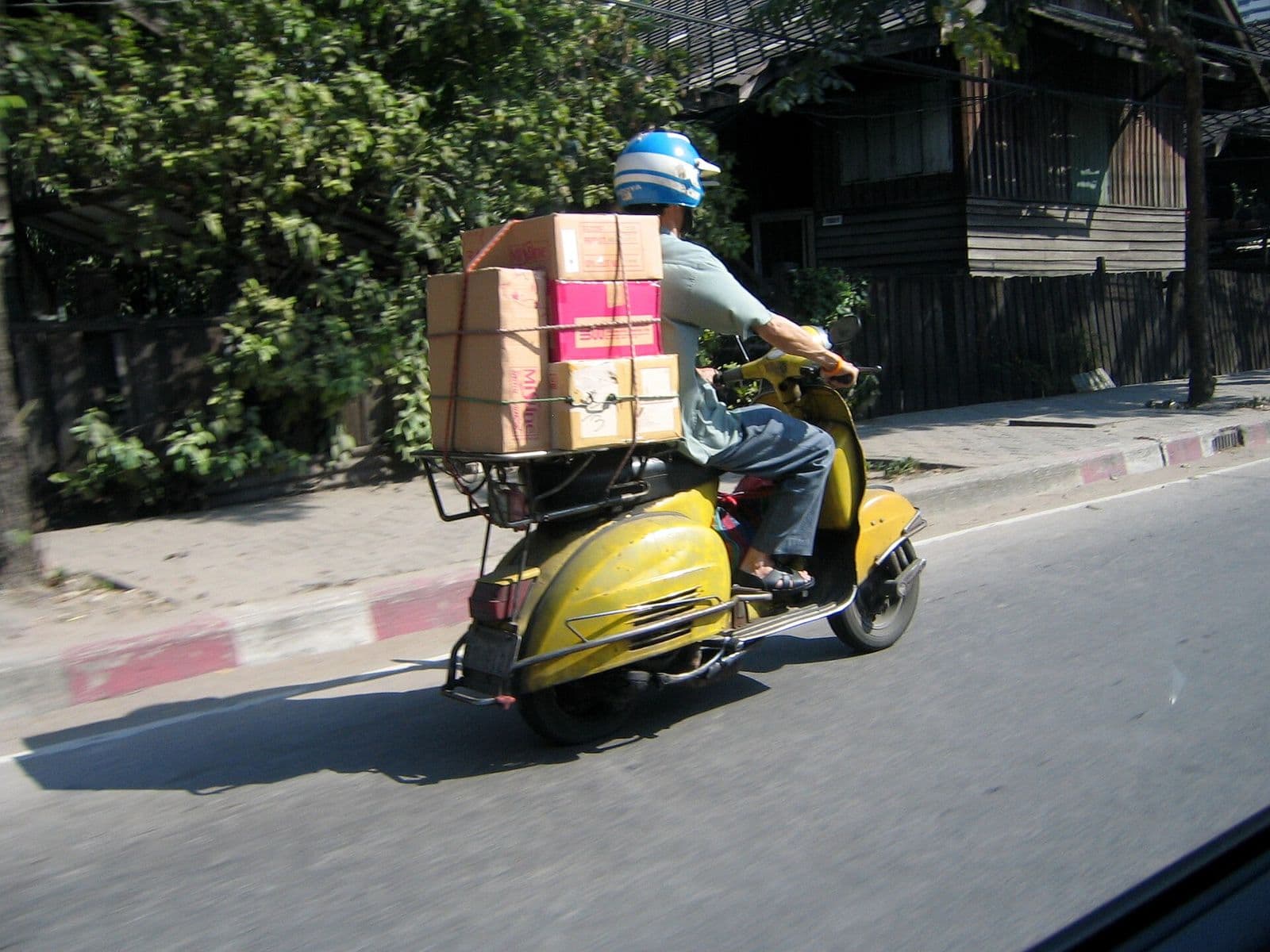 Courier riding a yellow scooter loaded with boxes
