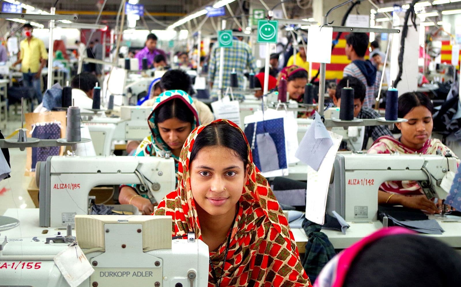 Garment workers at sewing machines on a busy factory floor